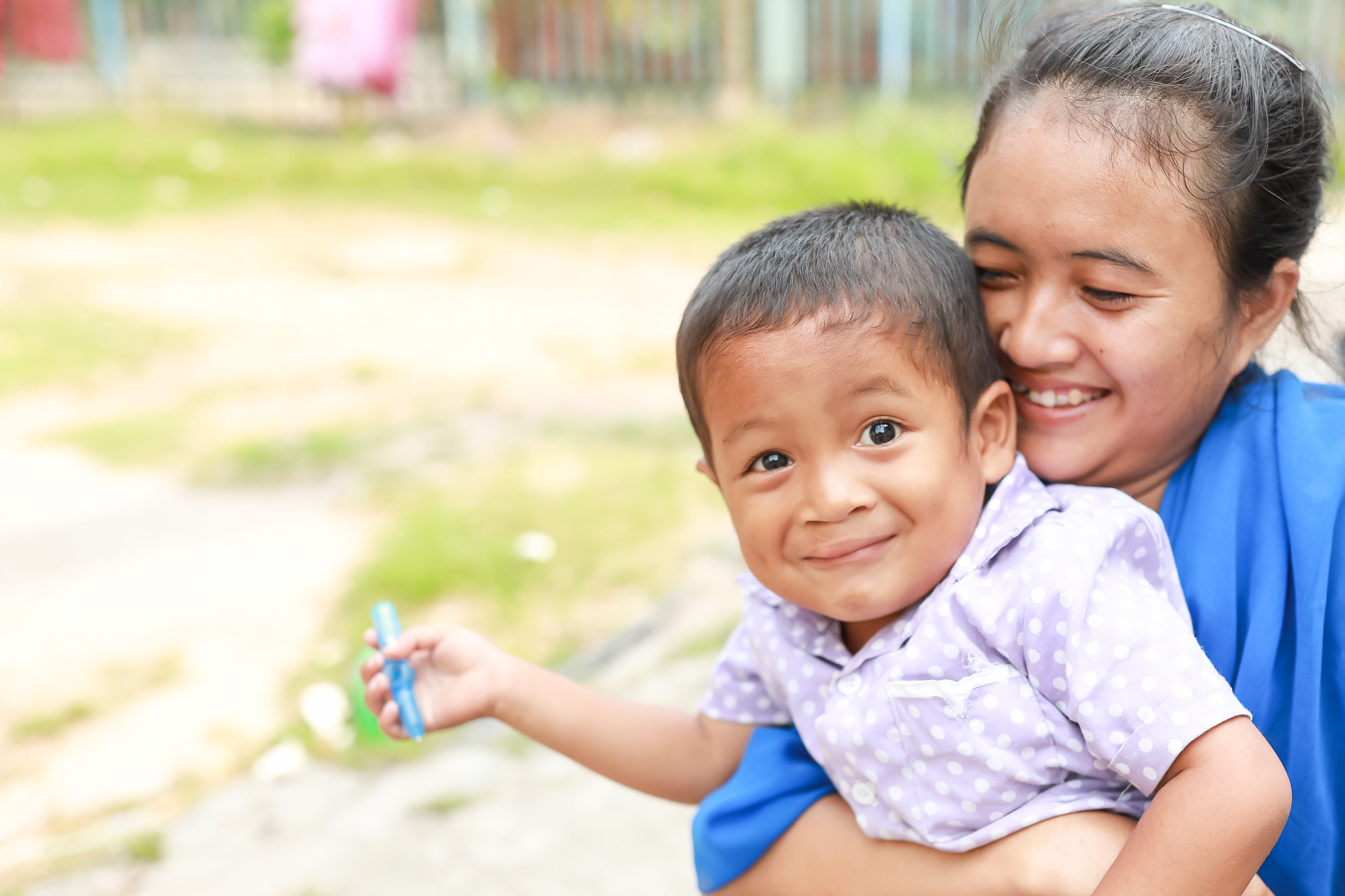 Darmawi smiling and holding her son Ikhsan after cleft surgery