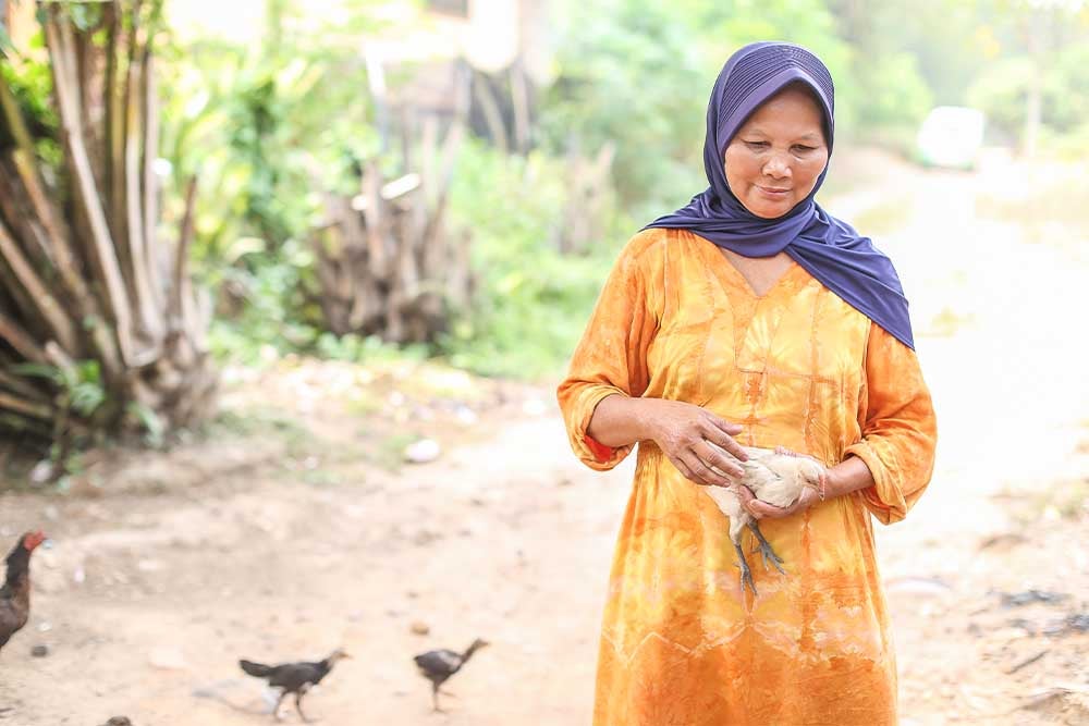 Jayem walking and holding a chicken after cleft surgery