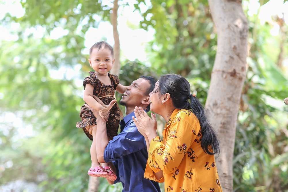 Yatna and Mawar smiling and holding Siti after her cleft surgery