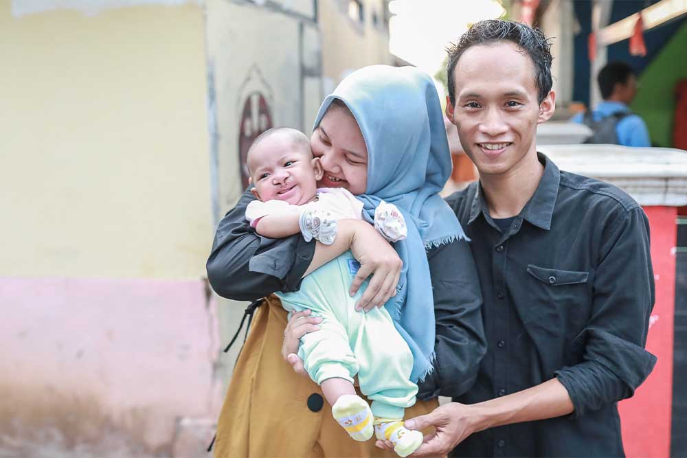 Haris and Nunung smiling and holding Rinda after her cleft surgery