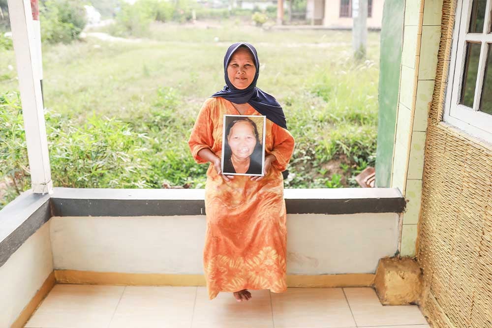 Jayem smiling and holding a picture of herself before cleft surgery