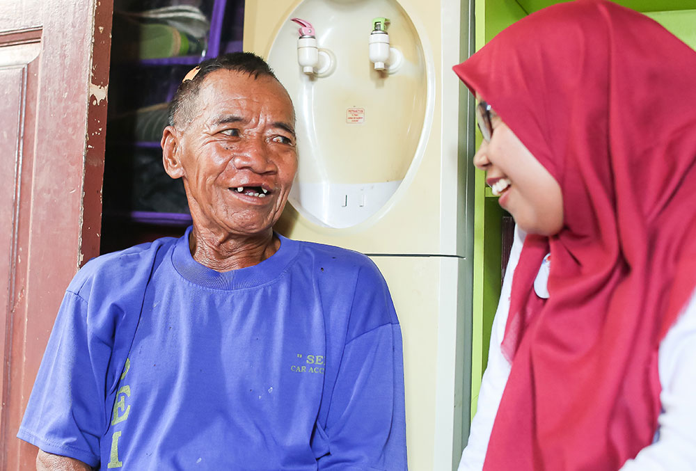 Endang smiling with and talking to an older Smile Train patient