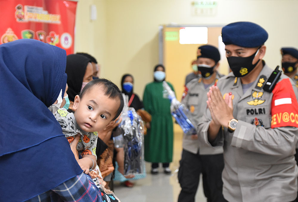 Indonesian police officer greeting a cleft-affected child and their mother after cleft surgery