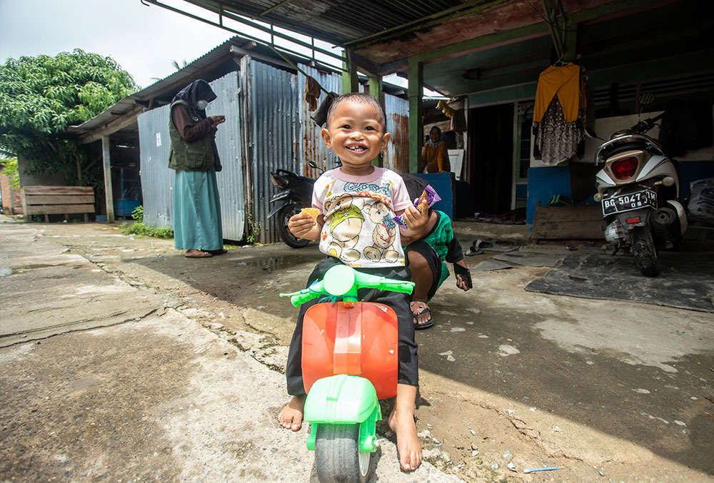 Karina smiling and riding her toy moped