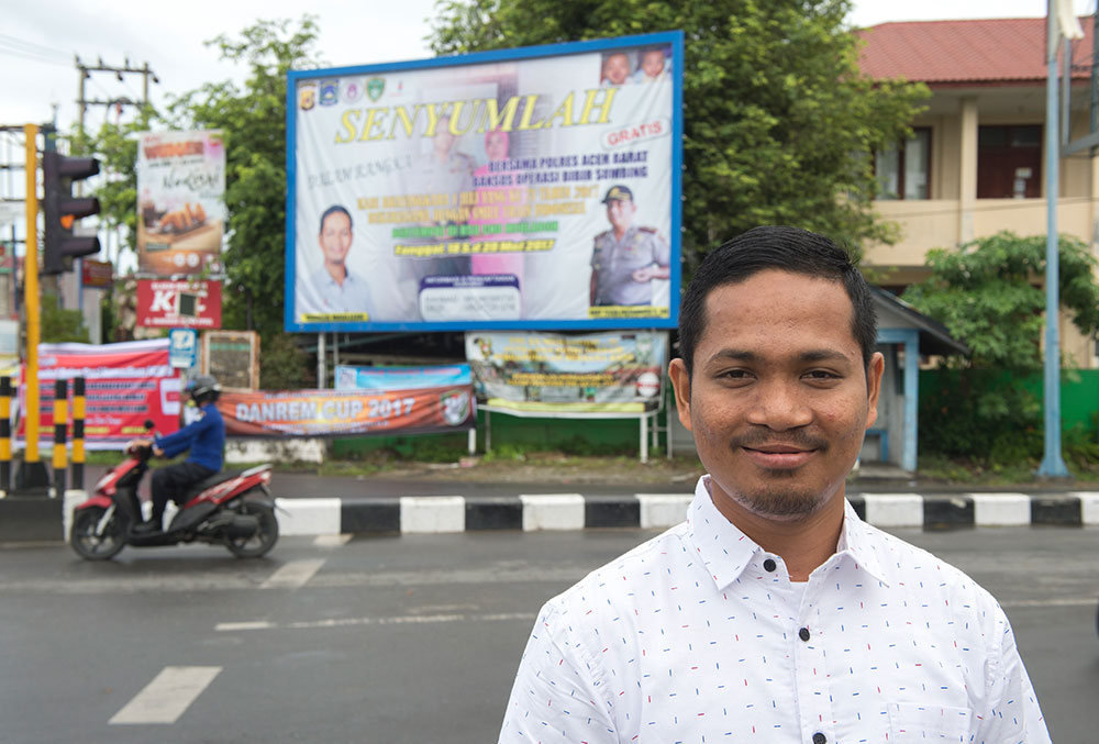 Rahmad berdiri di depan baliho Smile Train