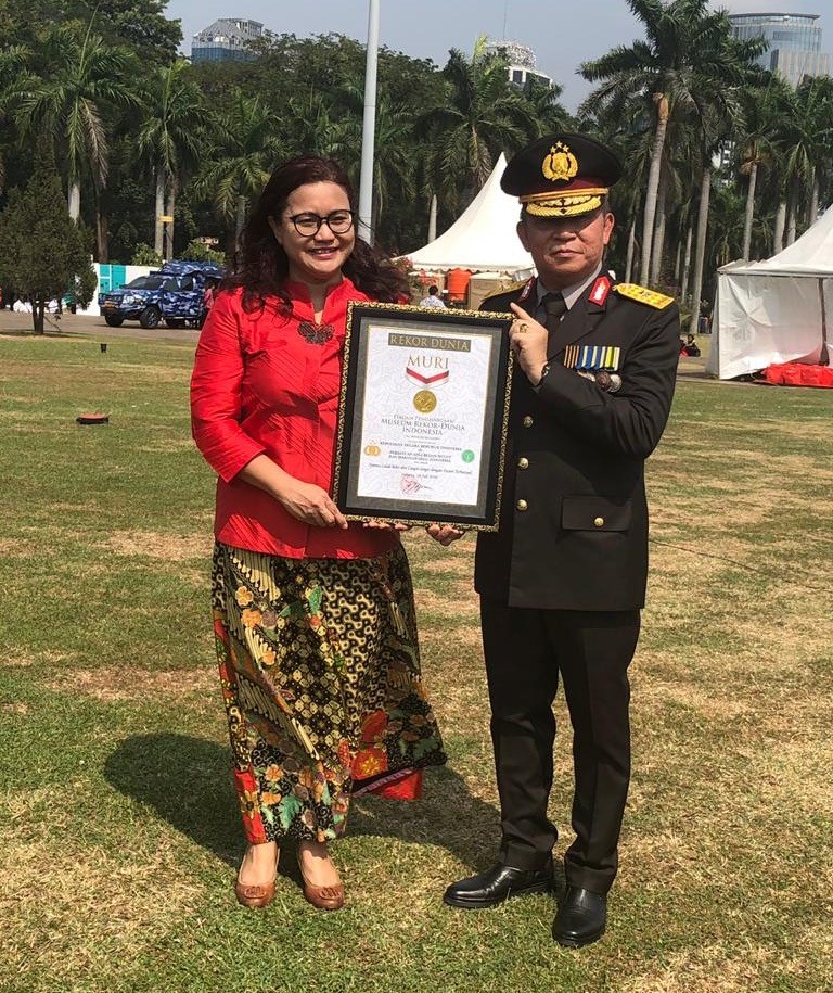 Deasy Larasati and an Indonesian soldier smiling and holding a Museum National Record certificate of achievement