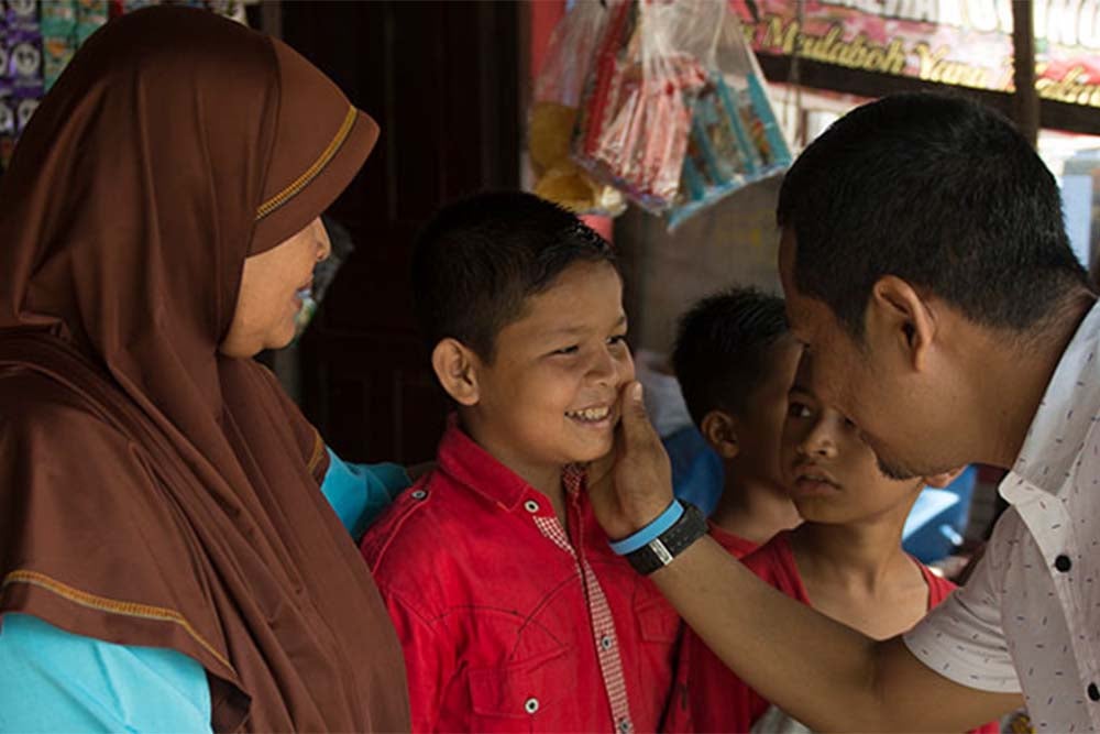 Rahmad smiling and comforting Deri and his mother