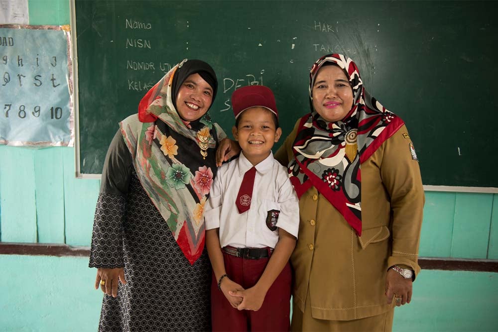 Deri smiling with his teachers