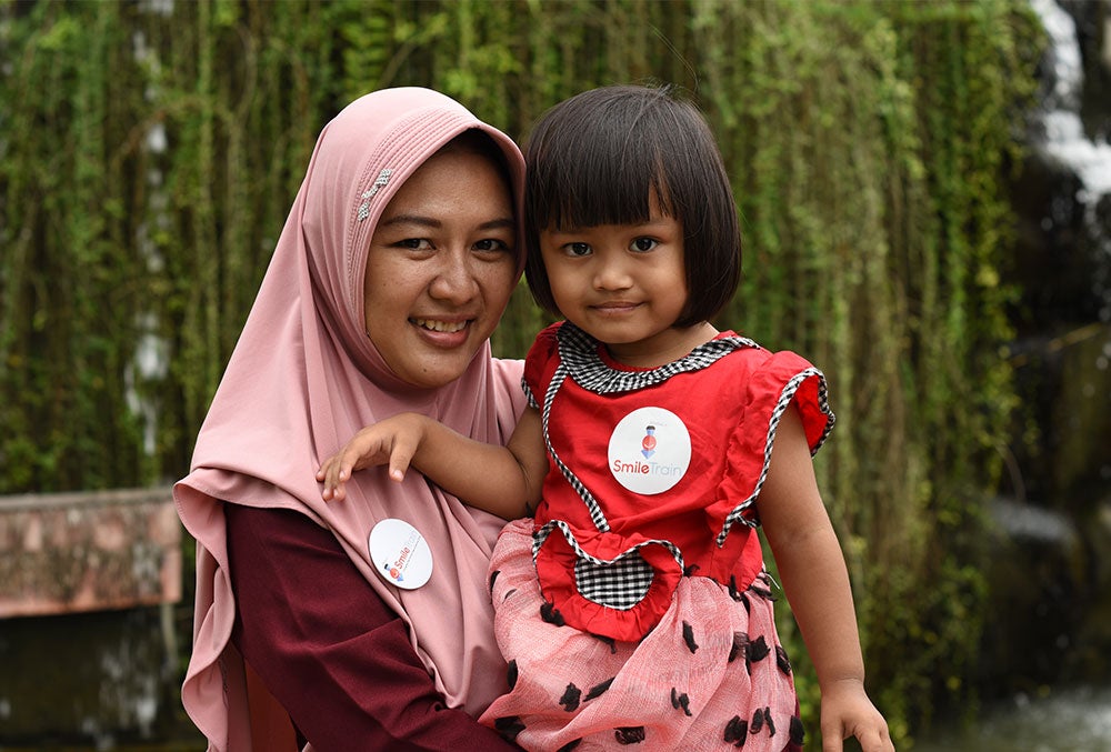 Ruri smiling and holding Khalisa after her cleft surgery