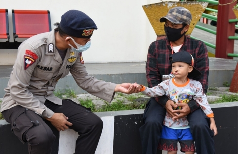 Petugas polisi Indonesia memegang tangan seorang anak penderita sumbing dan ayah mereka