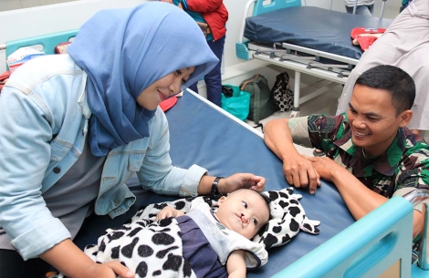 Indonesian police officer greeting a cleft-affected child and their mother after cleft surgery