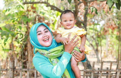 Mother smiling and holding her cleft-affected child after cleft surgery