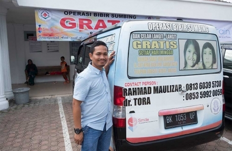 Rahmad tersenyum di samping van Smile Train miliknya