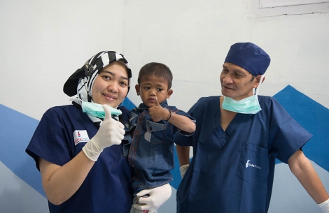 Two Smile Train partners smiling and giving thumbs up with a cleft-affected patient