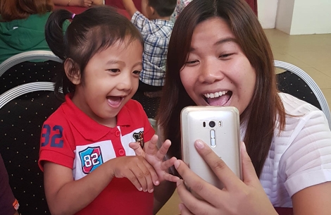 Cleft-affected patient and their mother smiling and using Smile Train's speech therapy app