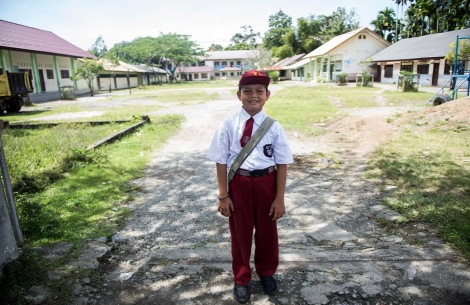 Deri tersenyum dan berdiri di luar sekolah setelah operasi sumbingnya