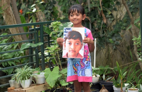 Yumna smiling and holding a picture of herself before cleft surgery