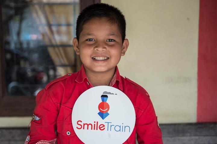 Deri smiling and holding a Smile Train sign