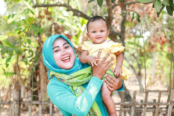 Mother smiling and holding her cleft-affected child after cleft surgery