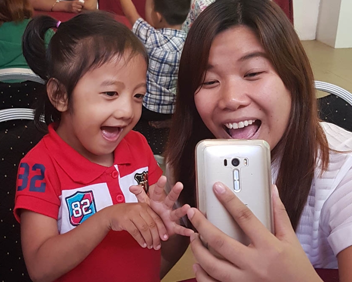 Cleft-affected patient and their mother smiling and using Smile Train's speech therapy app